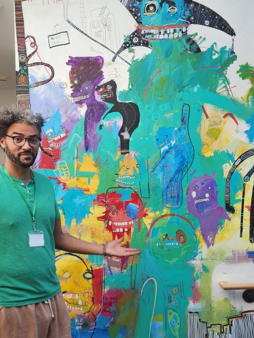 MOsley WOtta stands in from of a colorful mural.